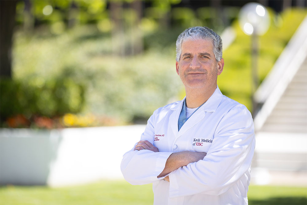 A portrait of Dr. Fernando Fleischman outside in a white medical coat with his arms crossed.
