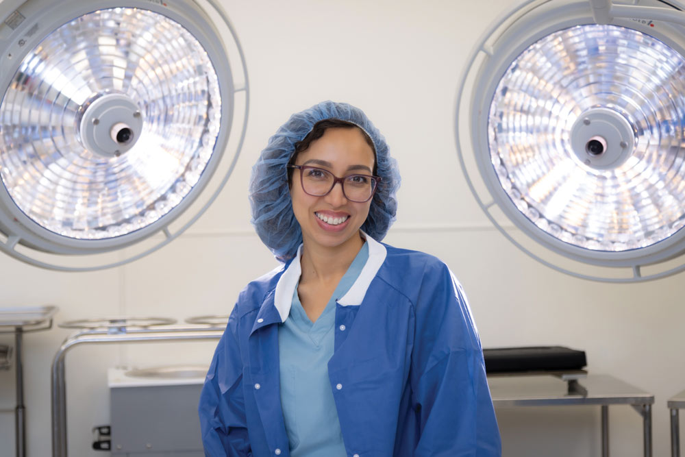Susana Rivera, a transplant recipient and nurse, wears scrubs and smiles in an operating room
