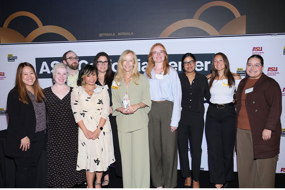 Group of women and one man smiling and holding awards.